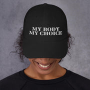 Black low-profile dad cap worn by a smiling model, embroidered in white with the words My Body My Choice.