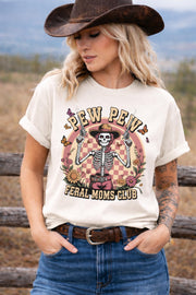 Western graphic t-shirt with skeleton cowgirl holding guns, “Pew Pew Feral Moms Club” text, and vintage floral design, worn in a country-style outdoor setting.