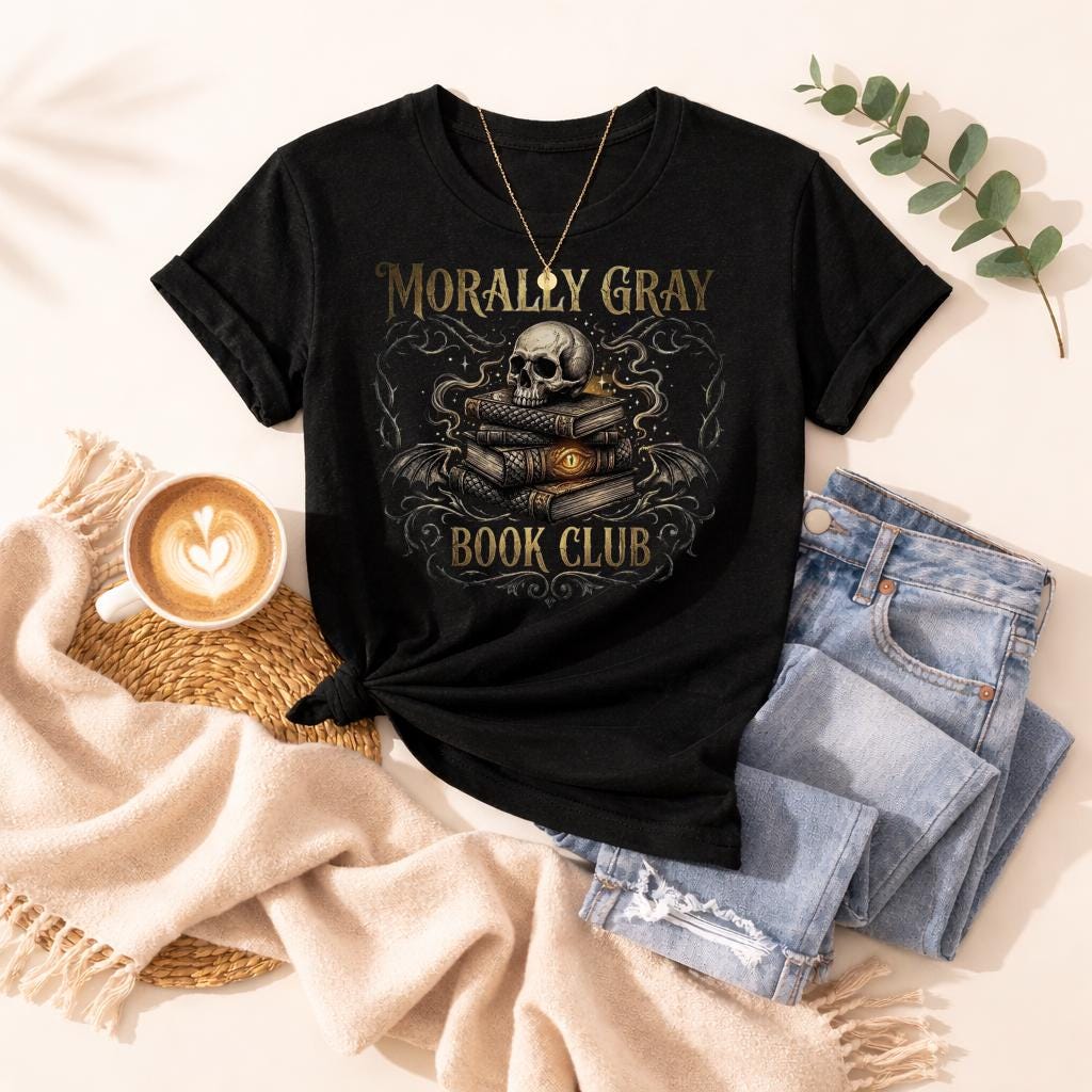 “Morally Gray Book Club” graphic t-shirt featuring a skull on stacked books with a glowing eye, styled in a dark academia aesthetic against a moody textured background.