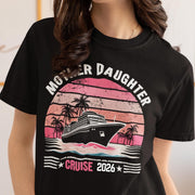 Woman wearing a Black Comfort Colors t-shirt featuring a retro Mother Daughter Cruise 2026 design with a vintage sunset, palm trees, and cruise ship graphic