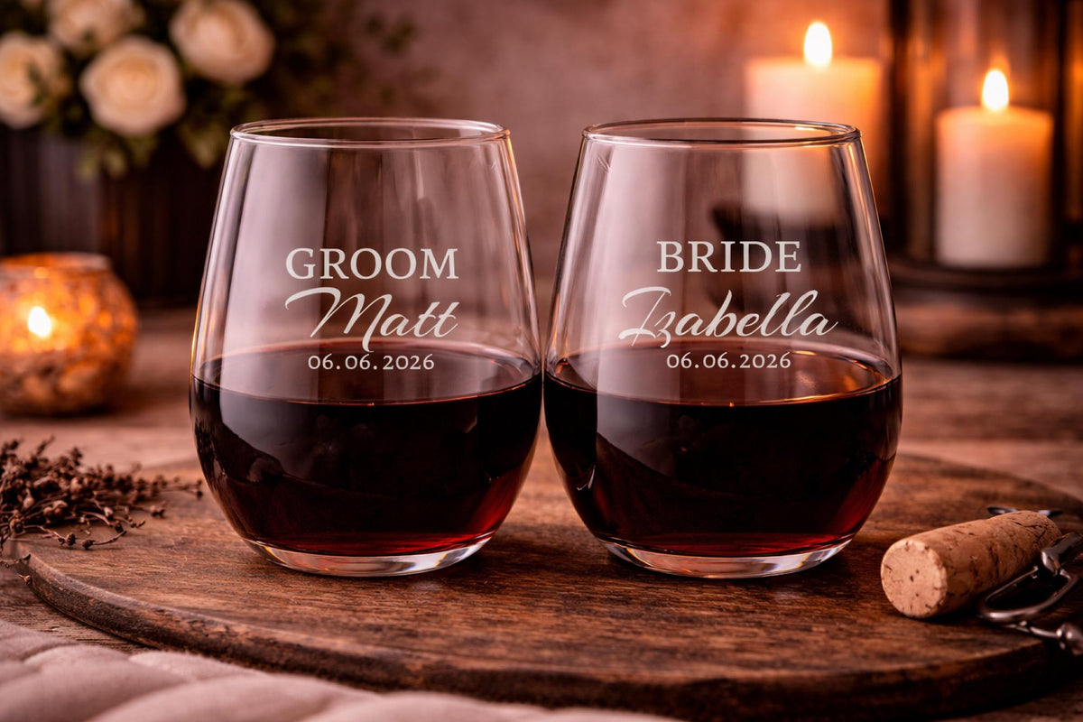 Clear stemless glasses with bride and groom names and date displayed in elegant script against a warm candlelit background