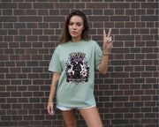 Woman wearing black graphic t-shirt with cute edgy bunny illustration and text Too Cute To Be Caught styled with denim shorts and accessories