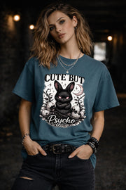 Graphic t-shirt featuring gothic bunny with glowing eyes and “Cute But Psycho” text, worn by model on beach with casual summer outfit