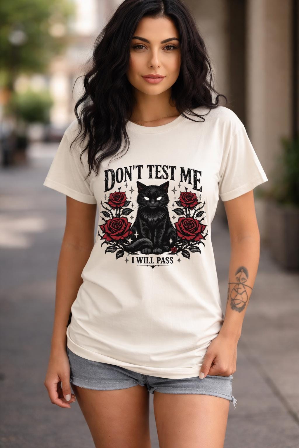Graphic t-shirt featuring black cat with red roses and “Don’t Test Me I Will Pass” text, styled on model with edgy casual outfit in urban setting