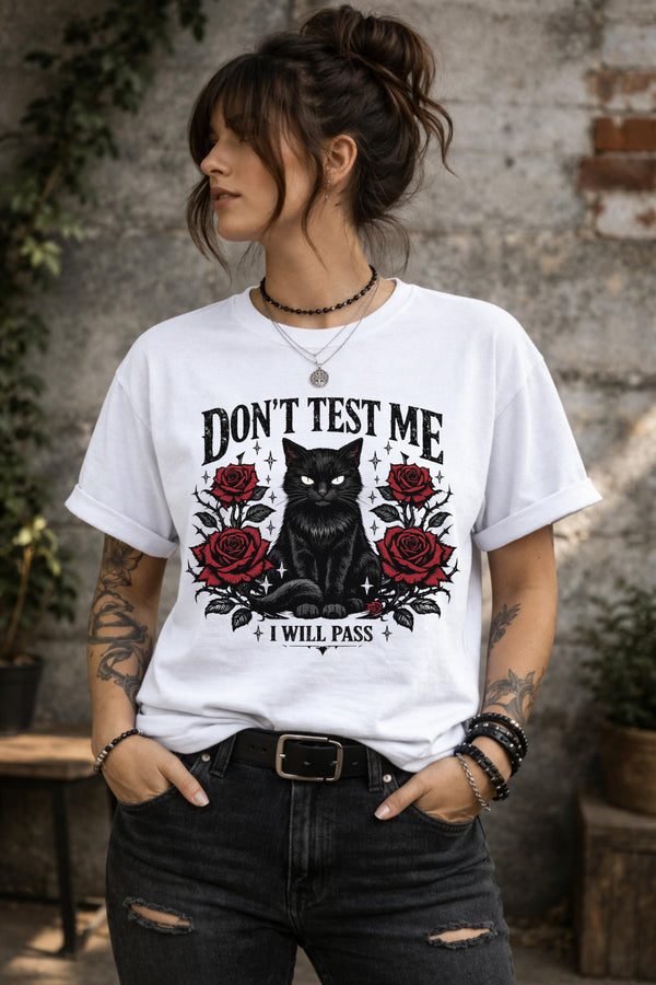 Graphic t-shirt featuring black cat with red roses and “Don’t Test Me I Will Pass” text, styled on model with edgy casual outfit in urban setting