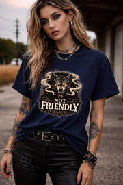 Graphic t-shirt featuring snarling wolf with glowing eyes and “Not Friendly” text, worn by model on beach with casual summer outfit