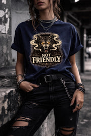 Graphic t-shirt featuring snarling wolf with glowing eyes and “Not Friendly” text, worn by model on beach with casual summer outfit