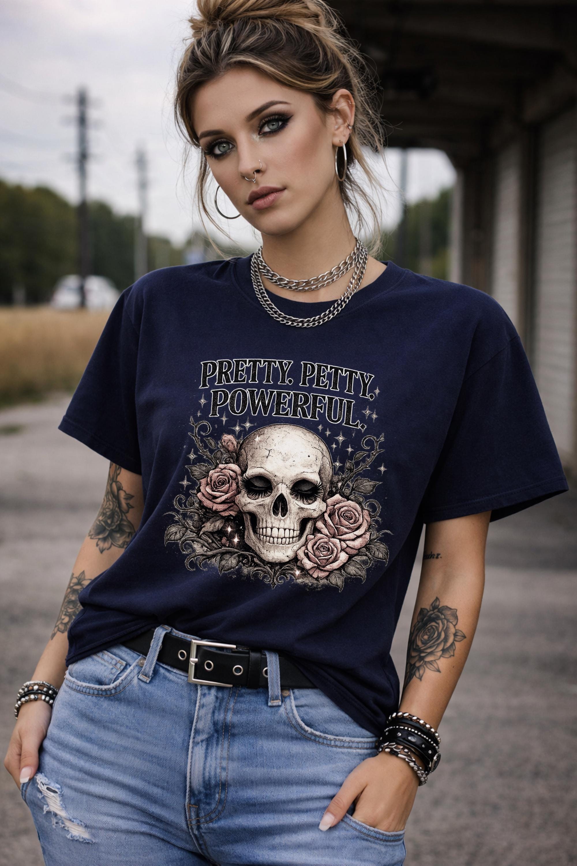 Graphic t-shirt featuring skull with roses and “Pretty Petty Powerful” text, styled on model with edgy streetwear aesthetic and dark neutral backdrop