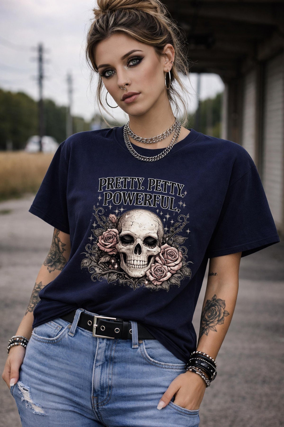 Graphic t-shirt featuring skull with roses and “Pretty Petty Powerful” text, styled on model with edgy streetwear aesthetic and dark neutral backdrop