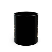Black ceramic 11oz mug featuring the fornt of the mug with a cute watercolor dragon with glowing eyes, styled on rustic wood table with candle, coffee beans, and cozy kitchen background
