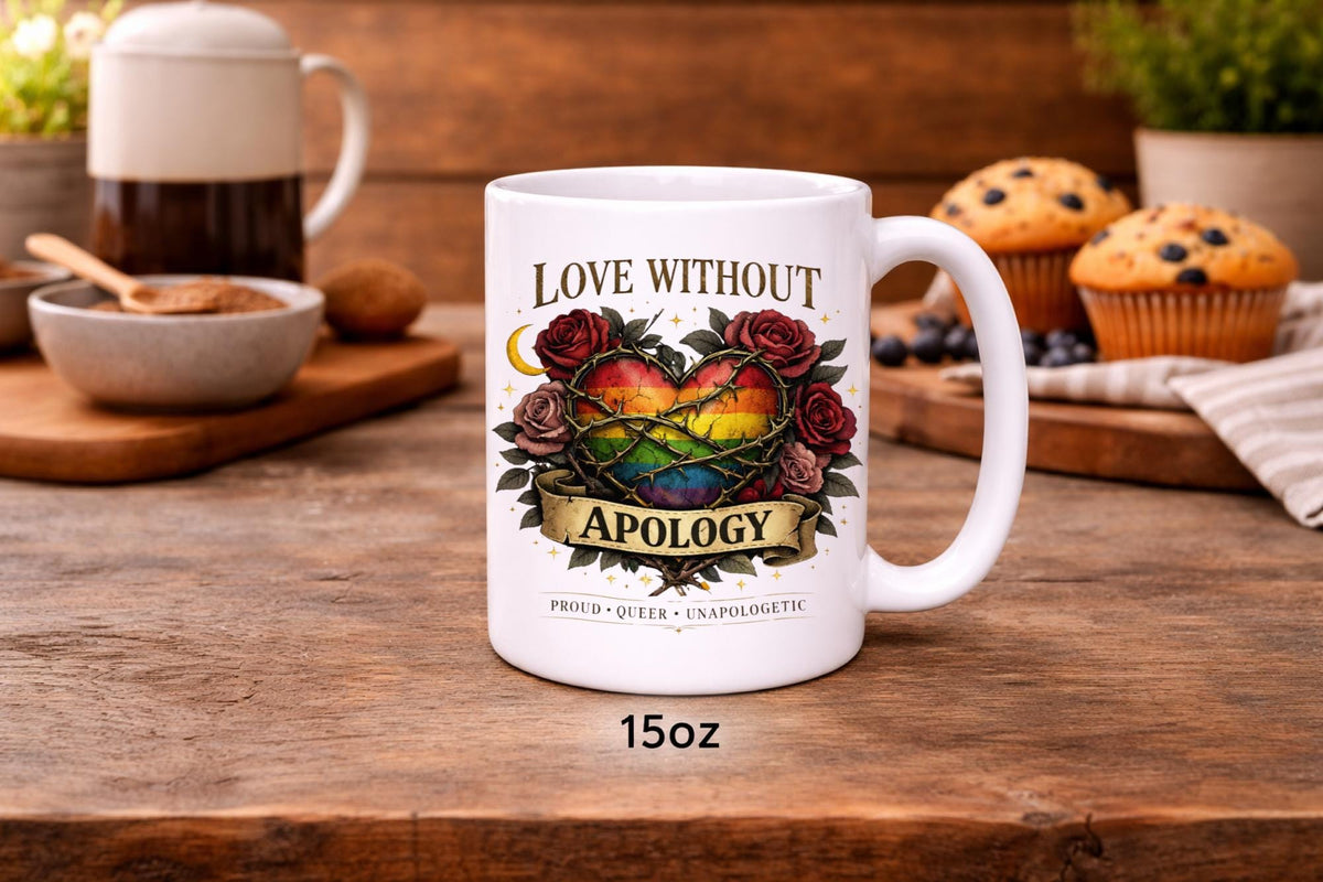 White ceramic 15oz mug featuring rainbow heart with roses and “Love Without Apology” text, styled on rustic kitchen table with muffins and coffee background