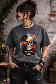 Dark gray graphic t-shirt featuring skull with rainbow accents and roses with “Love Is Not a Sin” text, styled on model with edgy alternative streetwear aesthetic