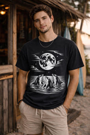 black t shirt with dolphin design under full moon, ocean scene graphic worn by male model