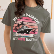 Woman wearing a Pepper Comfort Colors t-shirt featuring a retro Mother Daughter Cruise 2026 design with a vintage sunset, palm trees, and cruise ship graphic