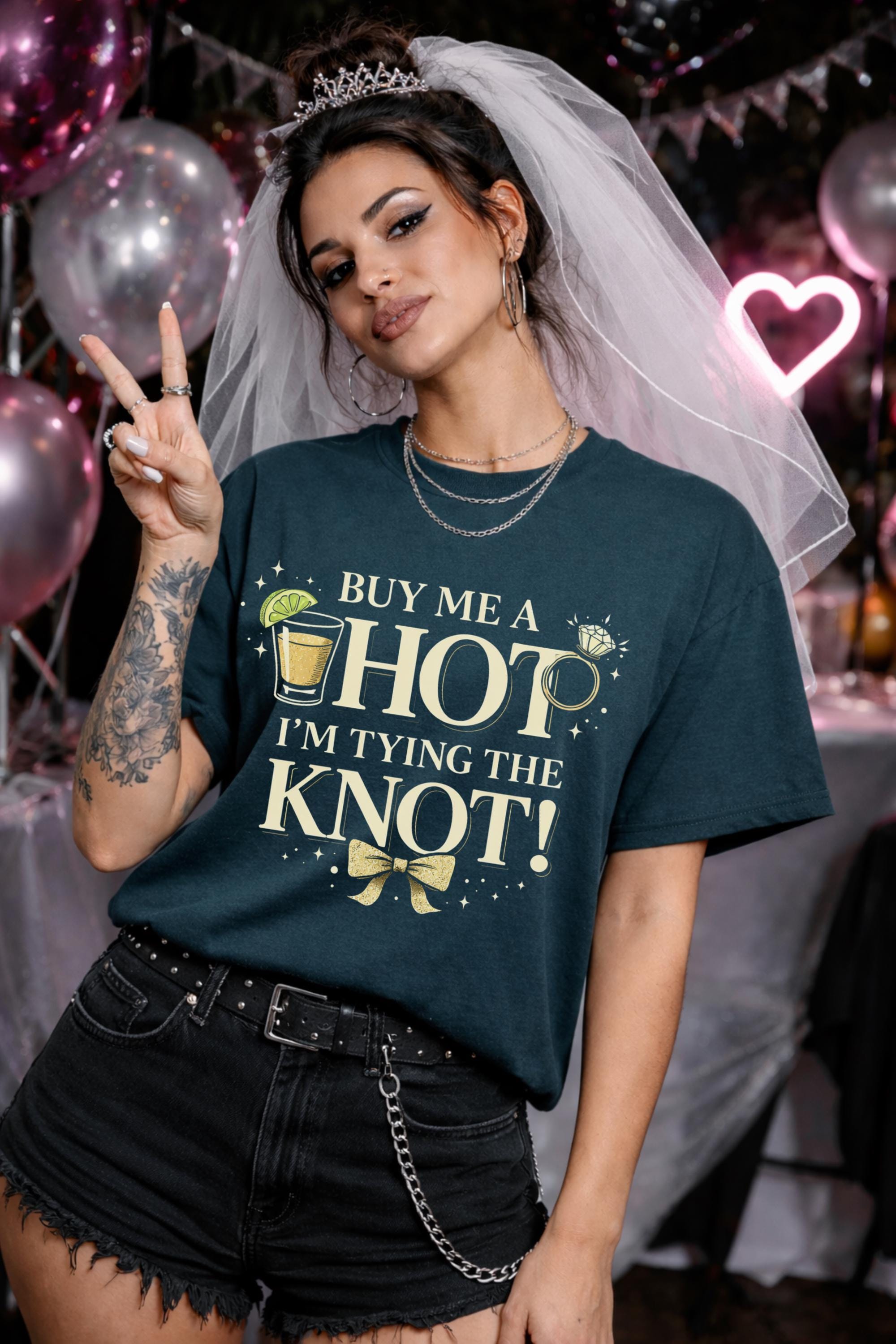 Bride bachelorette party shirt saying buy me a shot I’m tying the knot, woman wearing teal tee with gold text and cocktail graphic, fun bridal outfit