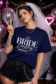 Bride loading bachelorette shirt mockup, woman wearing navy tee with “Bride Loading” text and progress bar design, bridal party outfit with veil and party background