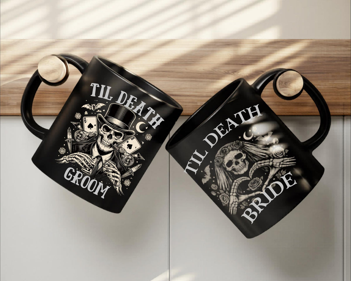 Black gothic coffee mugs featuring skeleton bride and groom artwork stacked together on wooden table with candlelight