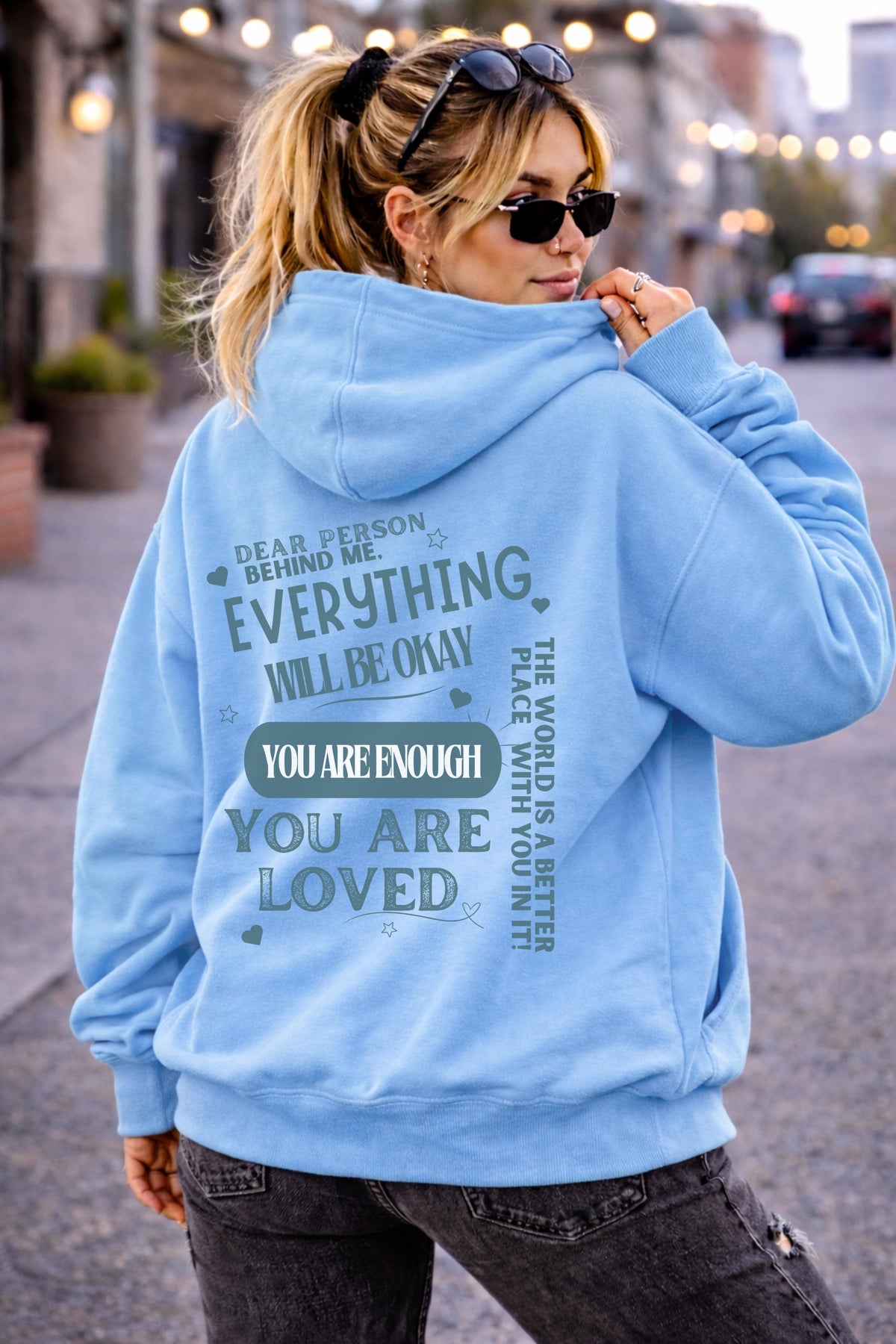 Woman wearing motivational hoodie featuring “you are enough” and “you are loved” message on the back