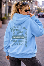 Woman wearing motivational hoodie featuring “you are enough” and “you are loved” message on the back
