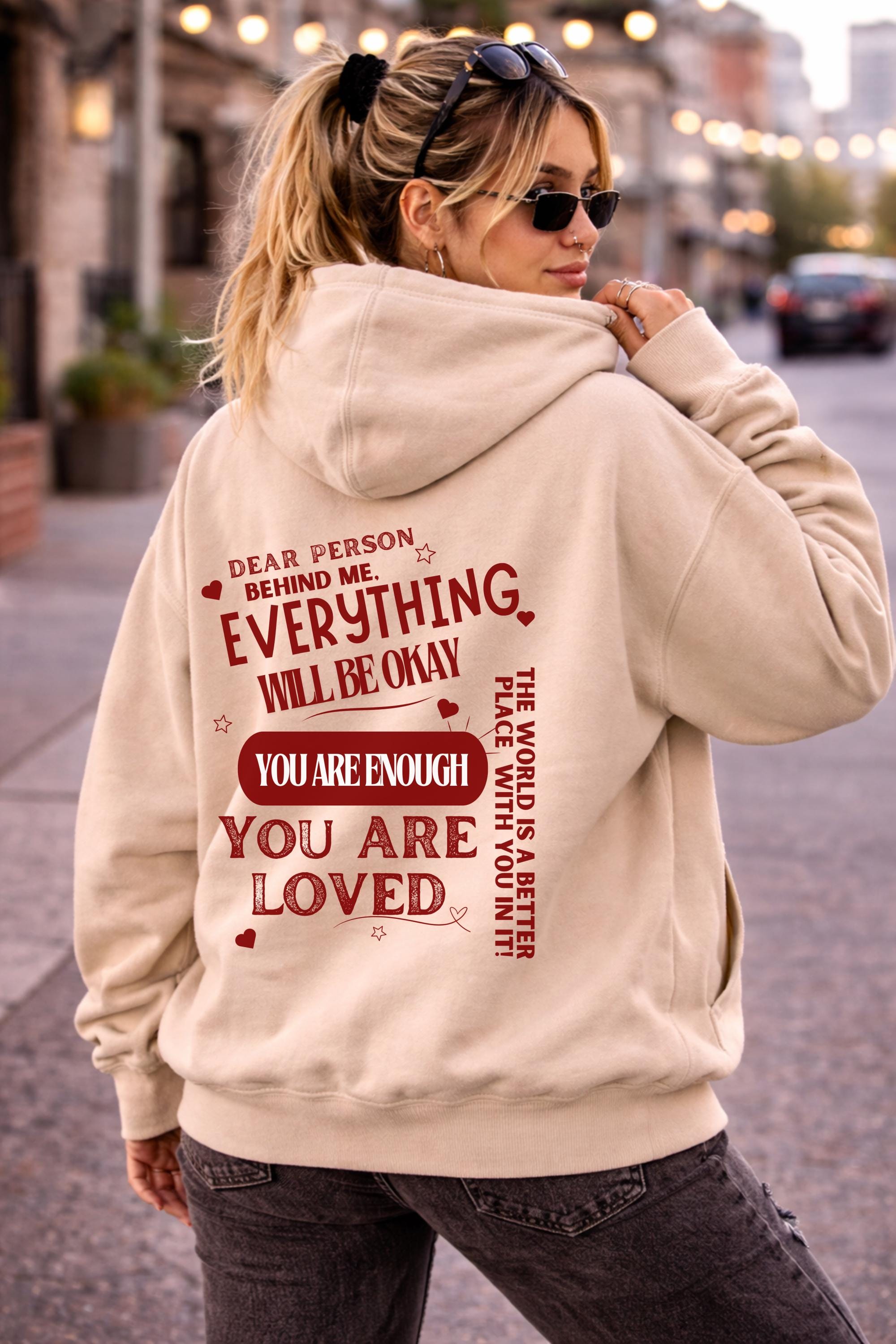 Woman wearing motivational hoodie featuring “you are enough” and “you are loved” message on the back