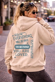Woman wearing motivational hoodie featuring “you are enough” and “you are loved” message on the back