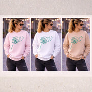 Woman modeling Gildan 18000 crewneck sweatshirt in pink, white, and sand colors showing front, back, and side views in outdoor lifestyle setting