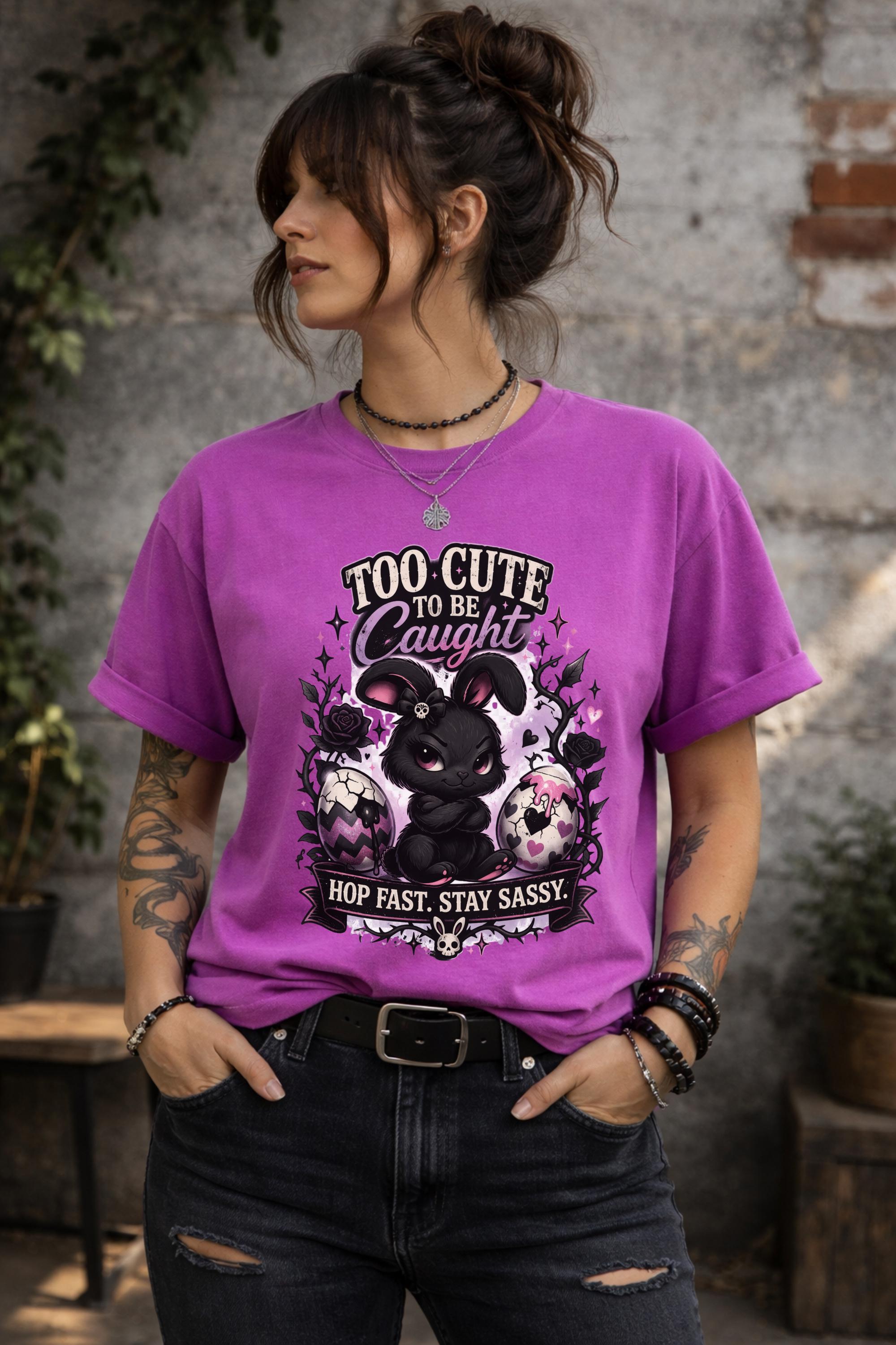 Woman wearing black graphic t-shirt with cute edgy bunny illustration and text Too Cute To Be Caught styled with denim jeans and accessories