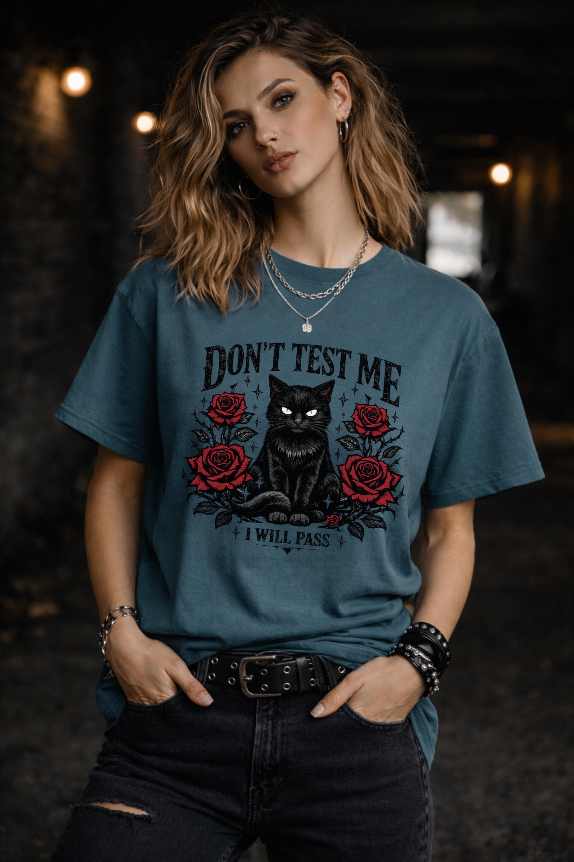 Graphic t-shirt featuring black cat with red roses and “Don’t Test Me I Will Pass” text, styled on model with edgy casual outfit in urban setting