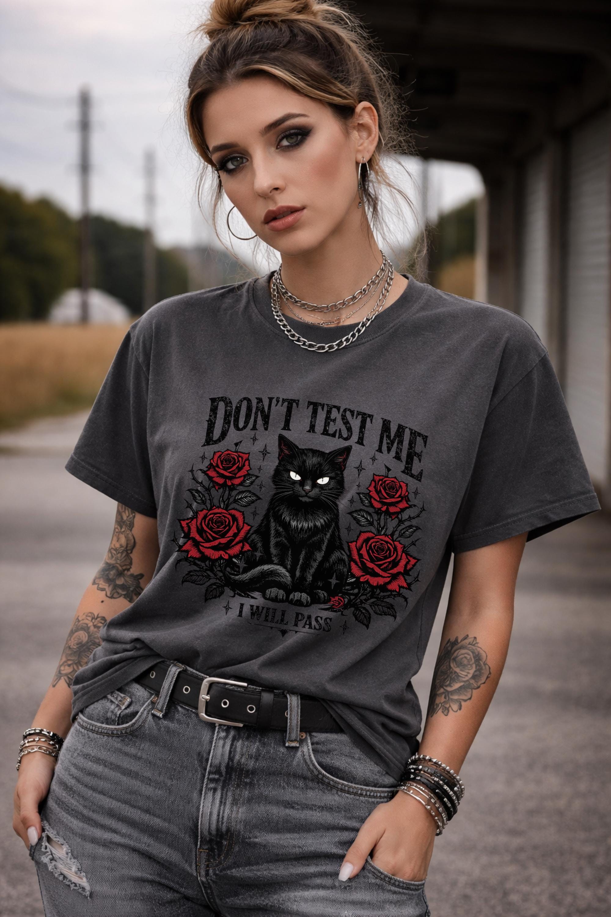 Graphic t-shirt featuring black cat with red roses and “Don’t Test Me I Will Pass” text, styled on model with edgy casual outfit in urban setting