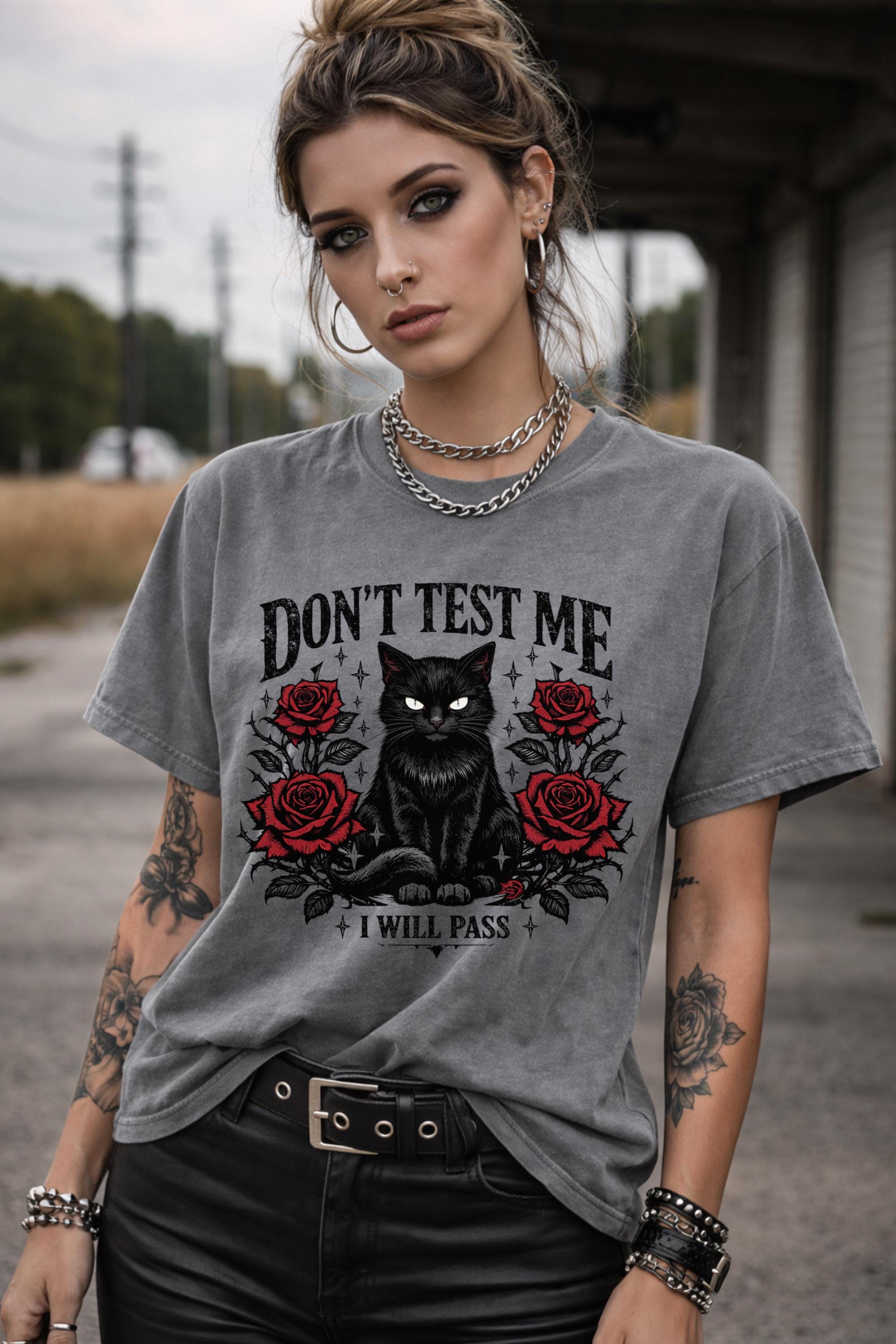 Graphic t-shirt featuring black cat with red roses and “Don’t Test Me I Will Pass” text, styled on model with edgy casual outfit in urban setting