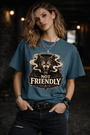 Graphic t-shirt featuring snarling wolf with glowing eyes and “Not Friendly” text, worn by model on beach with casual summer outfit