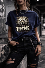 Graphic t-shirt featuring fierce leopard with bold “Try Me” text, styled on model with edgy casual outfit in outdoor setting
