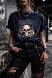 Graphic t-shirt featuring skull with roses and “Pretty Petty Powerful” text, styled on model with edgy streetwear aesthetic and dark neutral backdrop