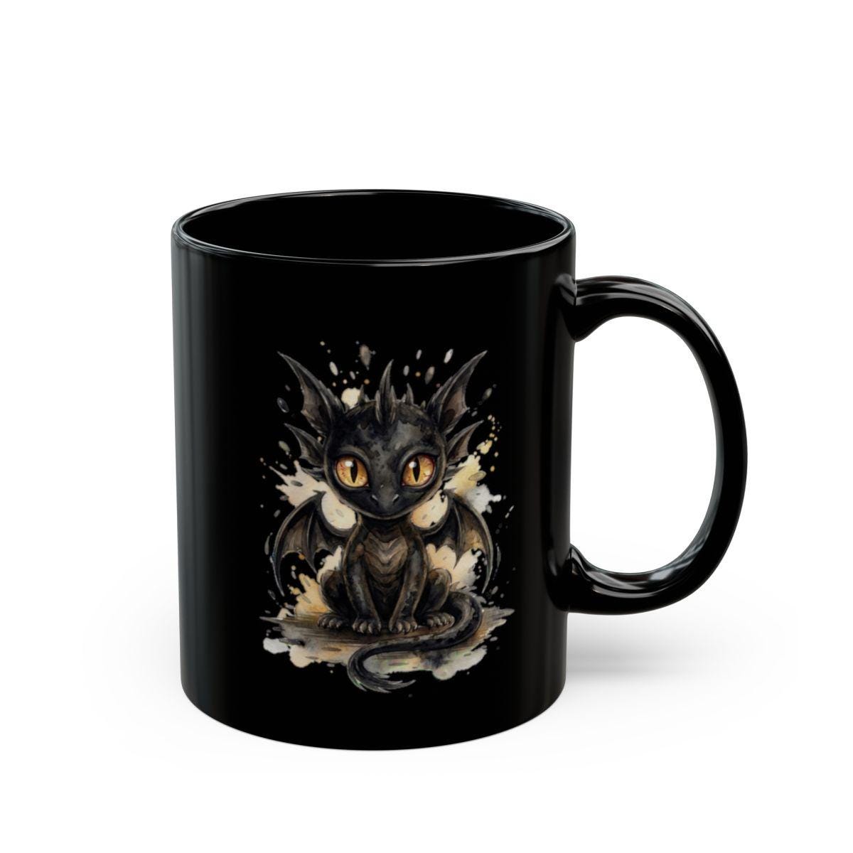 Black ceramic 15oz mug featuring cute watercolor dragon with glowing eyes, styled on rustic wood table with candle, coffee beans, and cozy kitchen background