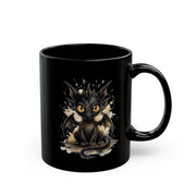Black ceramic 15oz mug featuring cute watercolor dragon with glowing eyes, styled on rustic wood table with candle, coffee beans, and cozy kitchen background