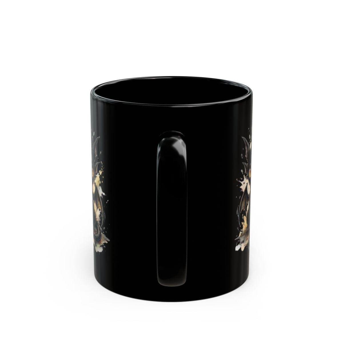 Black ceramic 11oz mug featuring the handle on the mug with a cute watercolor dragon with glowing eyes, styled on rustic wood table with candle, coffee beans, and cozy kitchen background