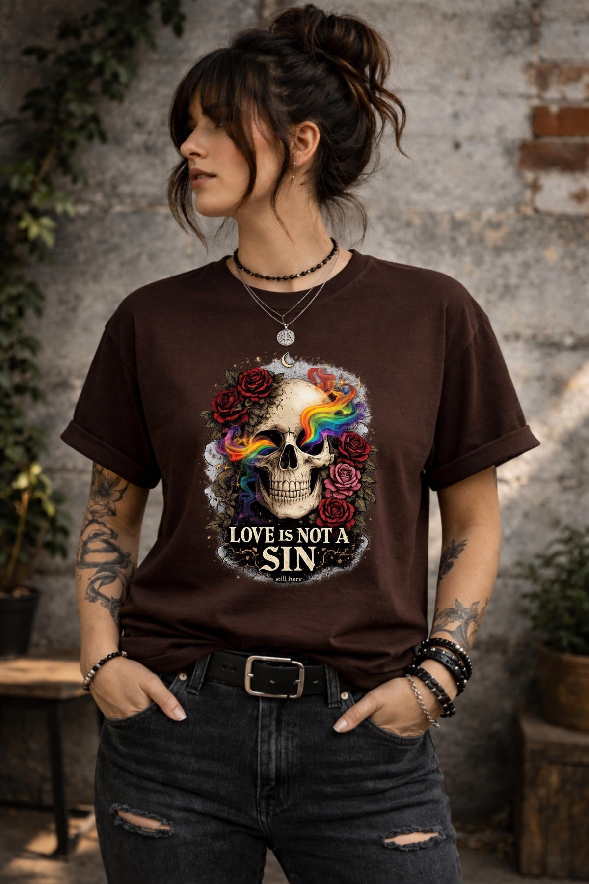 Graphic t-shirt featuring skull with rainbow accents and roses with “Love Is Not a Sin” text, styled on model with edgy alternative streetwear aesthetic