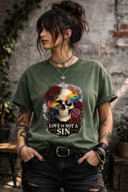 Graphic t-shirt featuring skull with rainbow accents and roses with “Love Is Not a Sin” text, styled on model with edgy alternative streetwear aesthetic