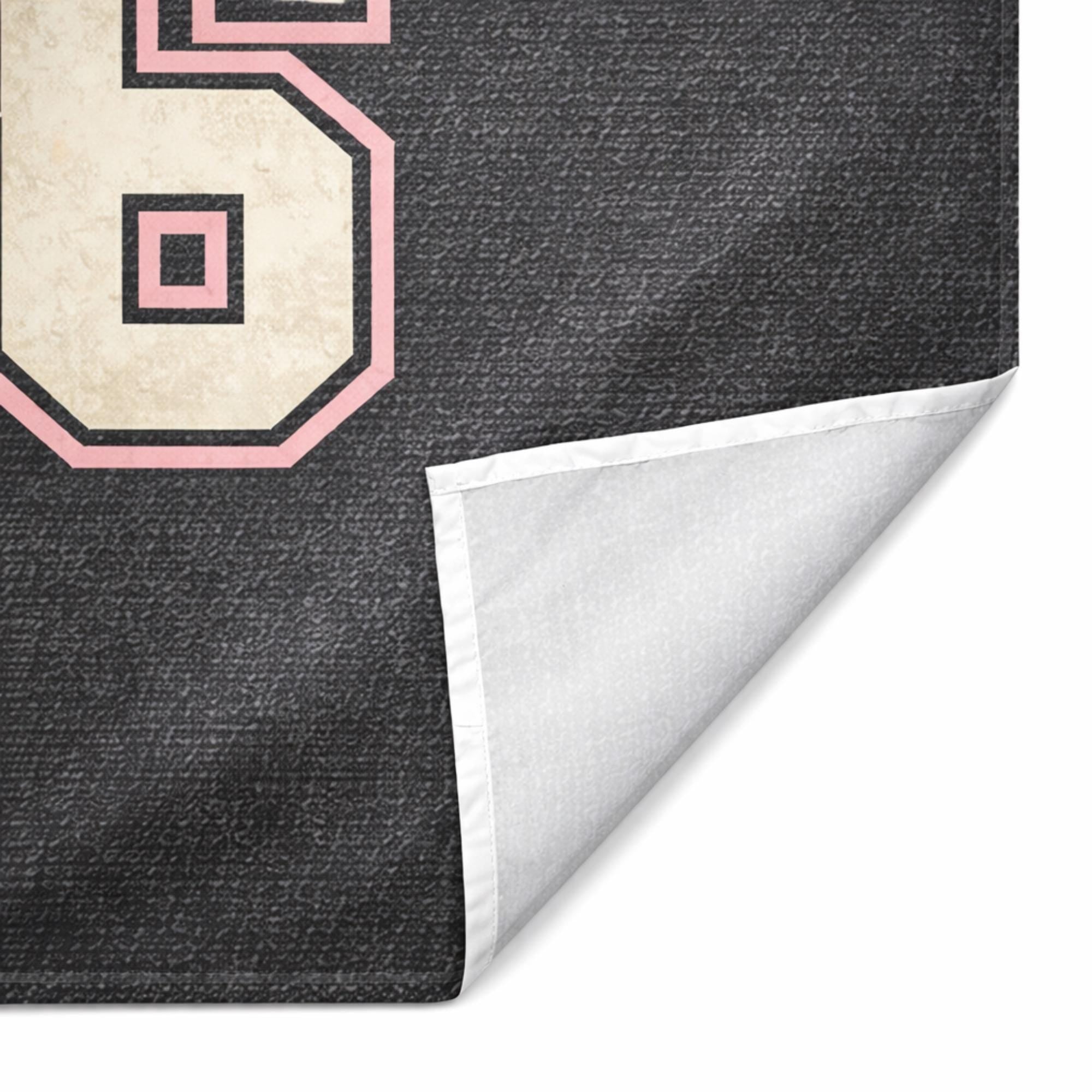 Close-up of graduation tapestry fabric showing stitched edge and soft material texture, black and pink Class of 2026 design detail