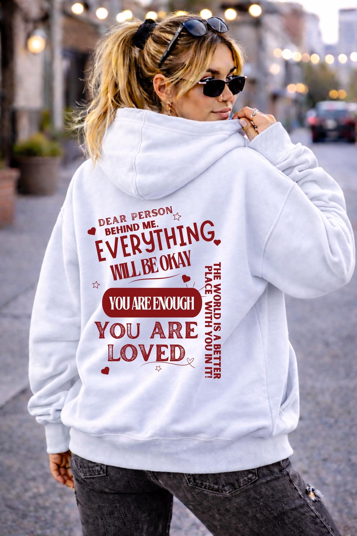 Woman wearing motivational hoodie featuring “you are enough” and “you are loved” message on the back