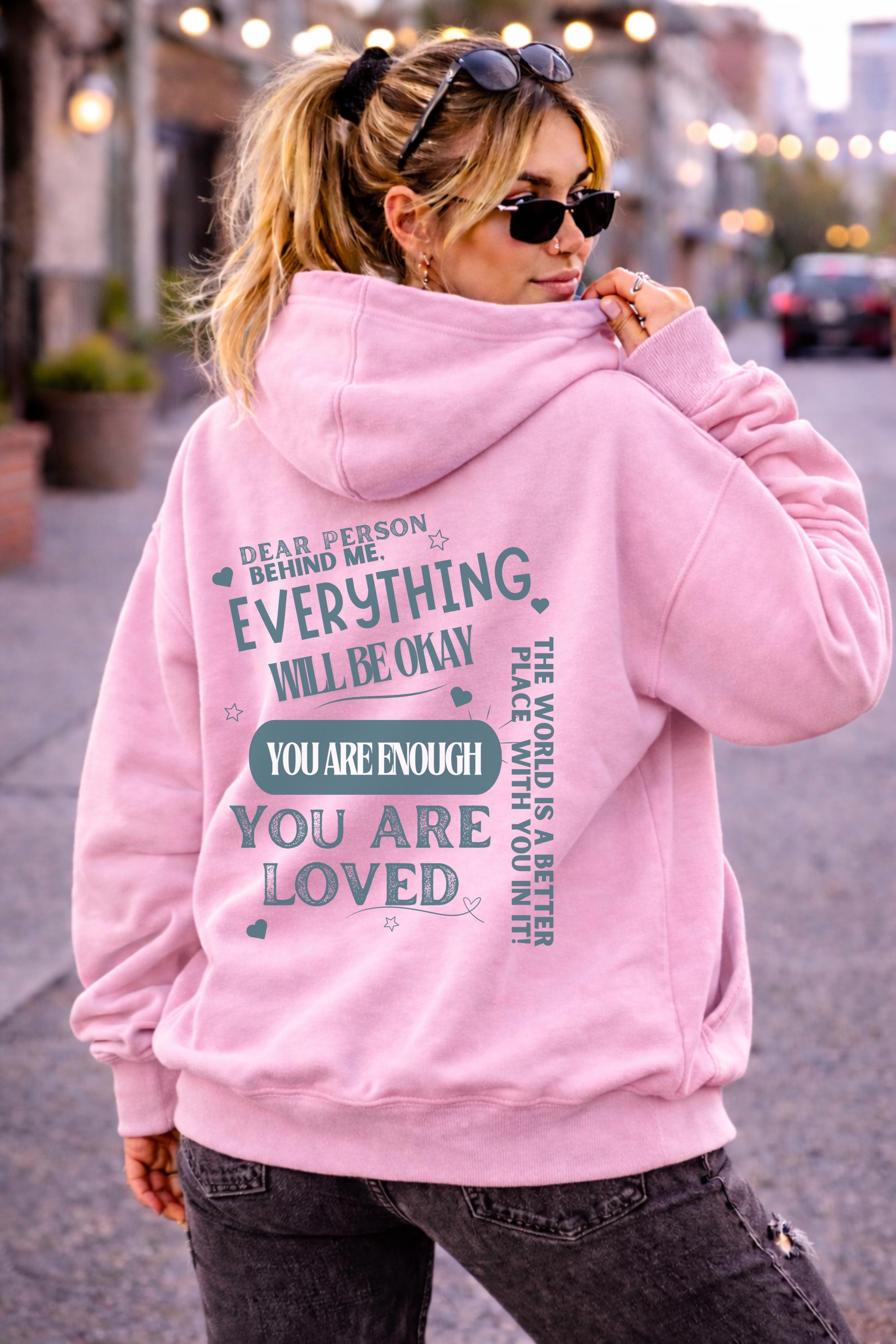 Woman wearing motivational hoodie featuring “you are enough” and “you are loved” message on the back