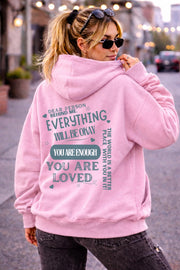 Woman wearing motivational hoodie featuring “you are enough” and “you are loved” message on the back