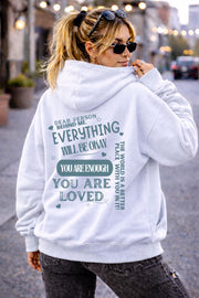 Woman wearing motivational hoodie featuring “you are enough” and “you are loved” message on the back