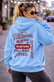 Woman wearing motivational hoodie featuring “you are enough” and “you are loved” message on the back