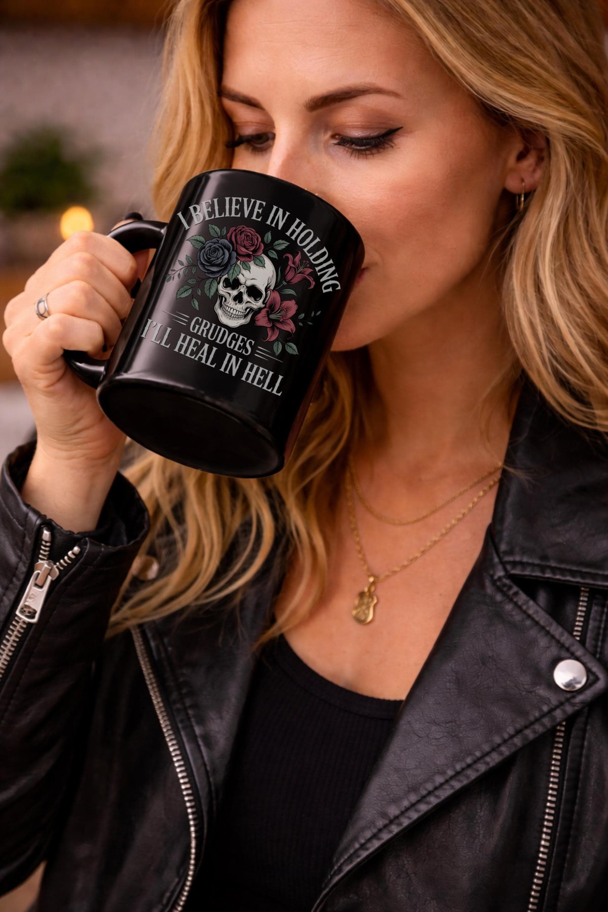 A women drinking coffee with text on the mug - I Believe in Holding Grudges Mug – Skull Floral Gothic Coffee Cup – Dark Humor Gift – 11oz 15oz Ceramic Mug