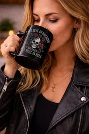 A women drinking coffee with text on the mug - I Believe in Holding Grudges Mug – Skull Floral Gothic Coffee Cup – Dark Humor Gift – 11oz 15oz Ceramic Mug