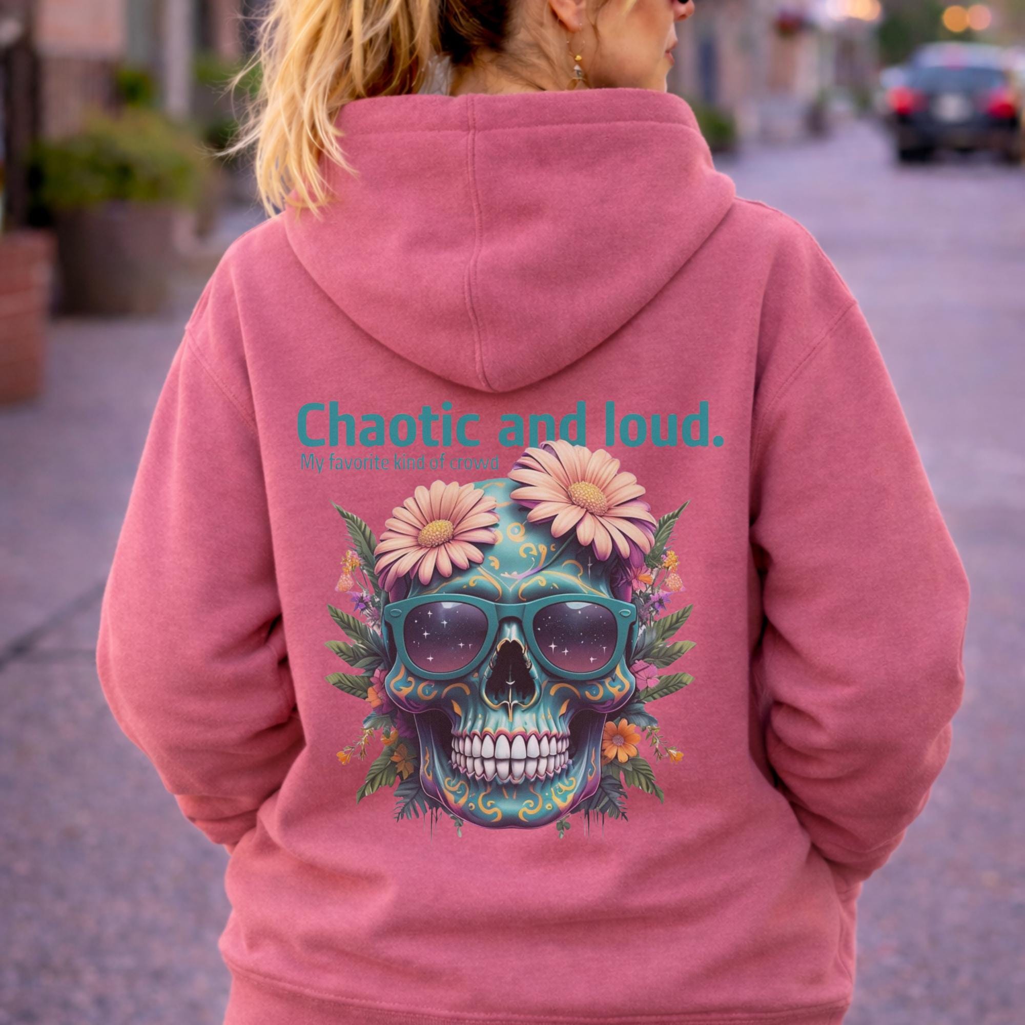 Back view of woman wearing a dusty rose Premium Pullover Hoodie Cotton Heritage M2580 featuring a colorful floral skull with sunglasses design and the text “Chaotic and loud, my favorite kind of crowd” printed on the back