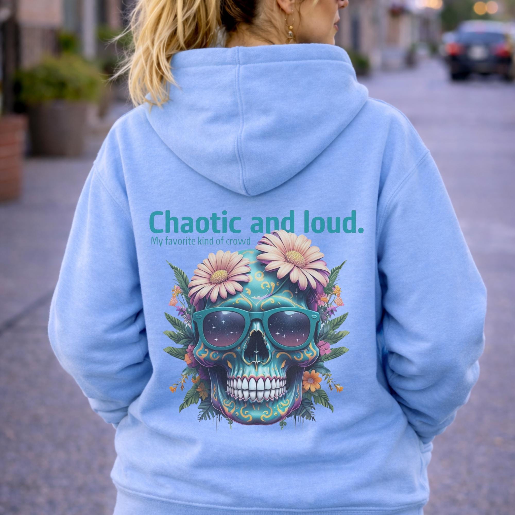 Back view of woman wearing a sky blue Premium Pullover Hoodie Cotton Heritage M2580 featuring a colorful floral skull with sunglasses design and the text “Chaotic and loud, my favorite kind of crowd” printed on the back