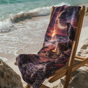 Gothic beach towel with raven and crescent moon design draped over wooden chair on sandy beach at sunset