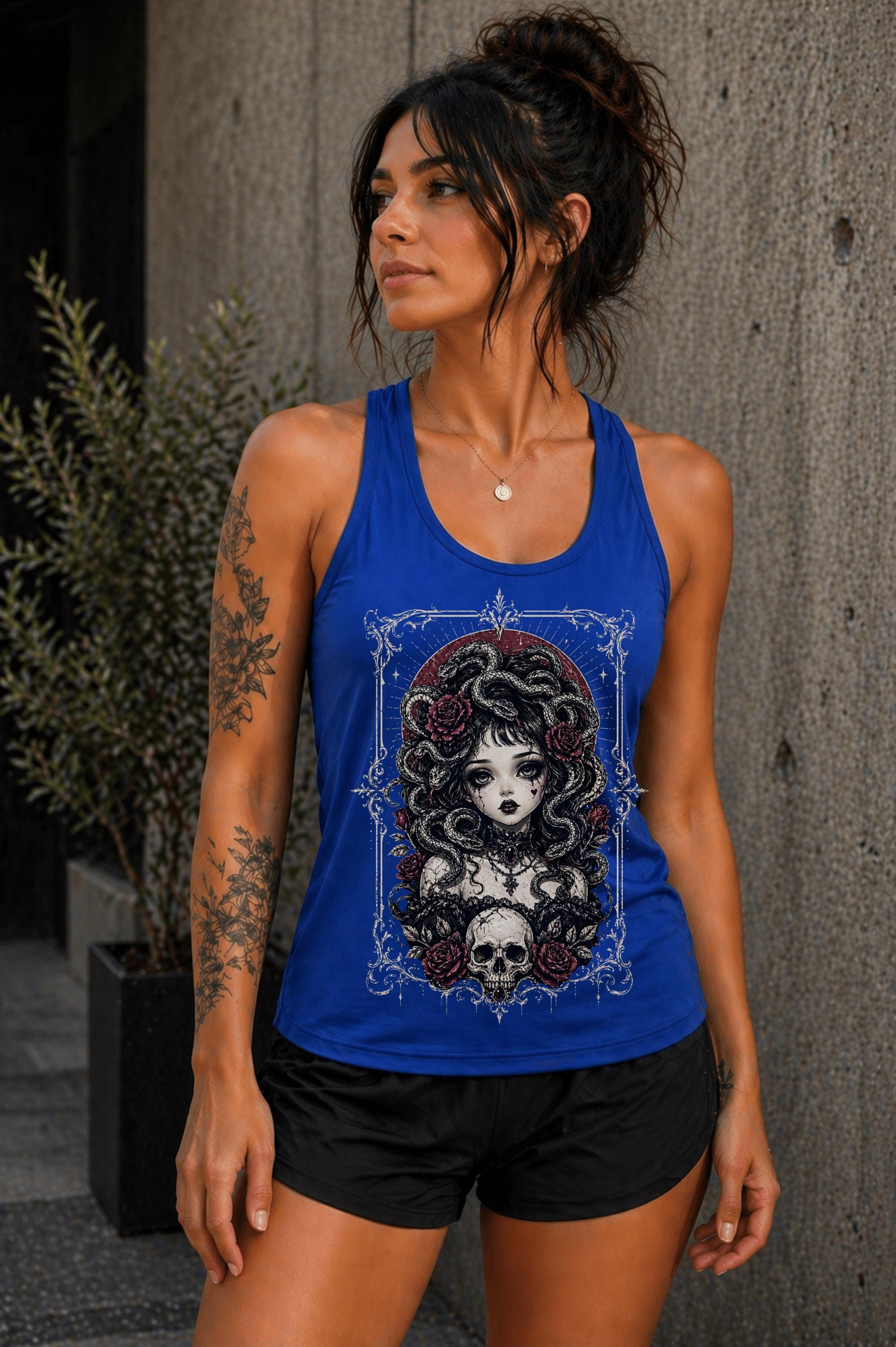 Woman wearing blue racerback tank top with gothic Medusa snake hair skull and roses graphic